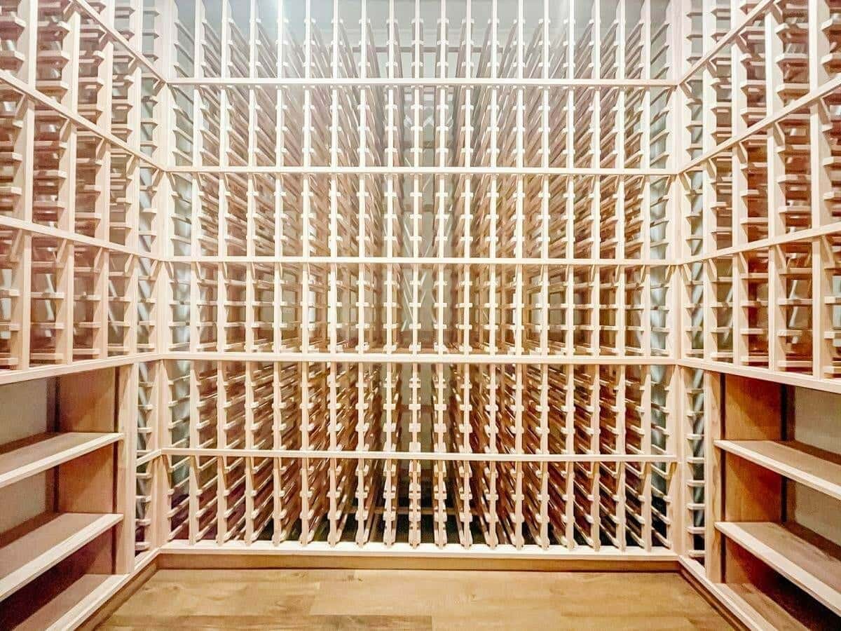 Empty wooden wine racks wrap around three walls above a wood floor.