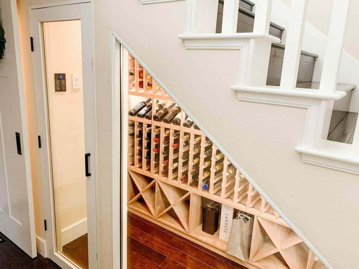Wooden bottle slots and diamond bins follow the angle of a staircase behind glass.