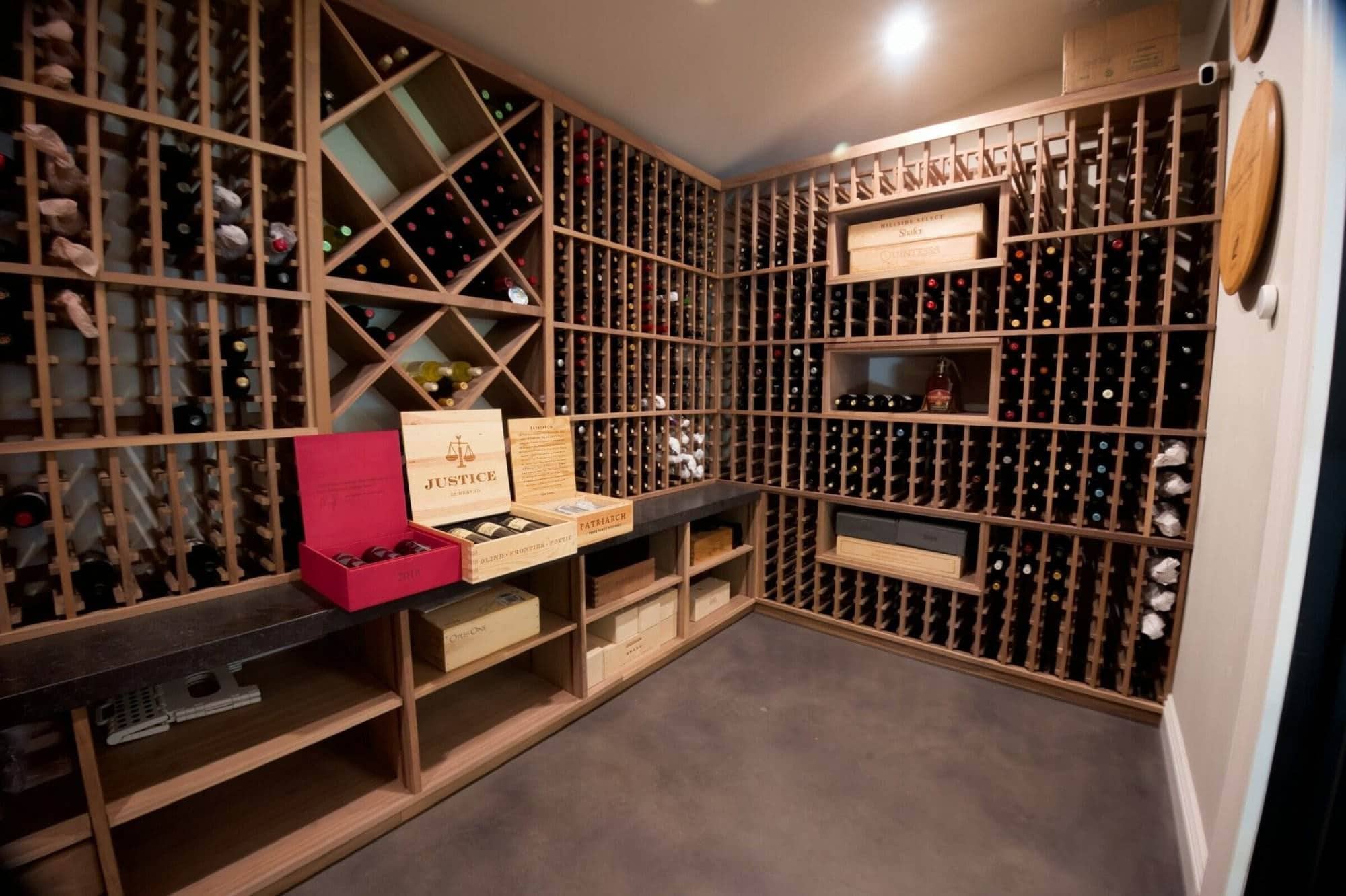 Wooden diamond bins and bottle slots surround open wine cases on a cellar counter.