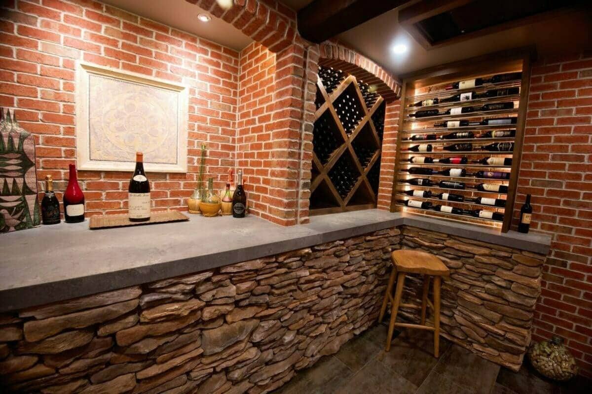 A stone-faced cellar bar sits beside brick walls and label-forward bottle racks.