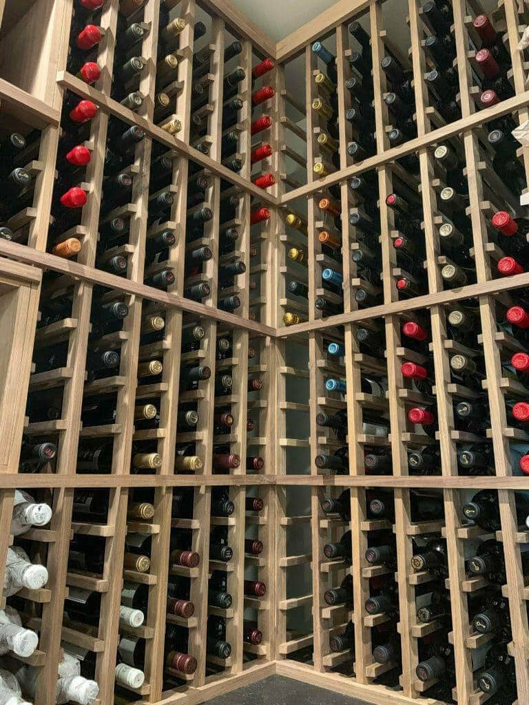 Rows of bottle necks fill tall wooden racks around a cellar corner.
