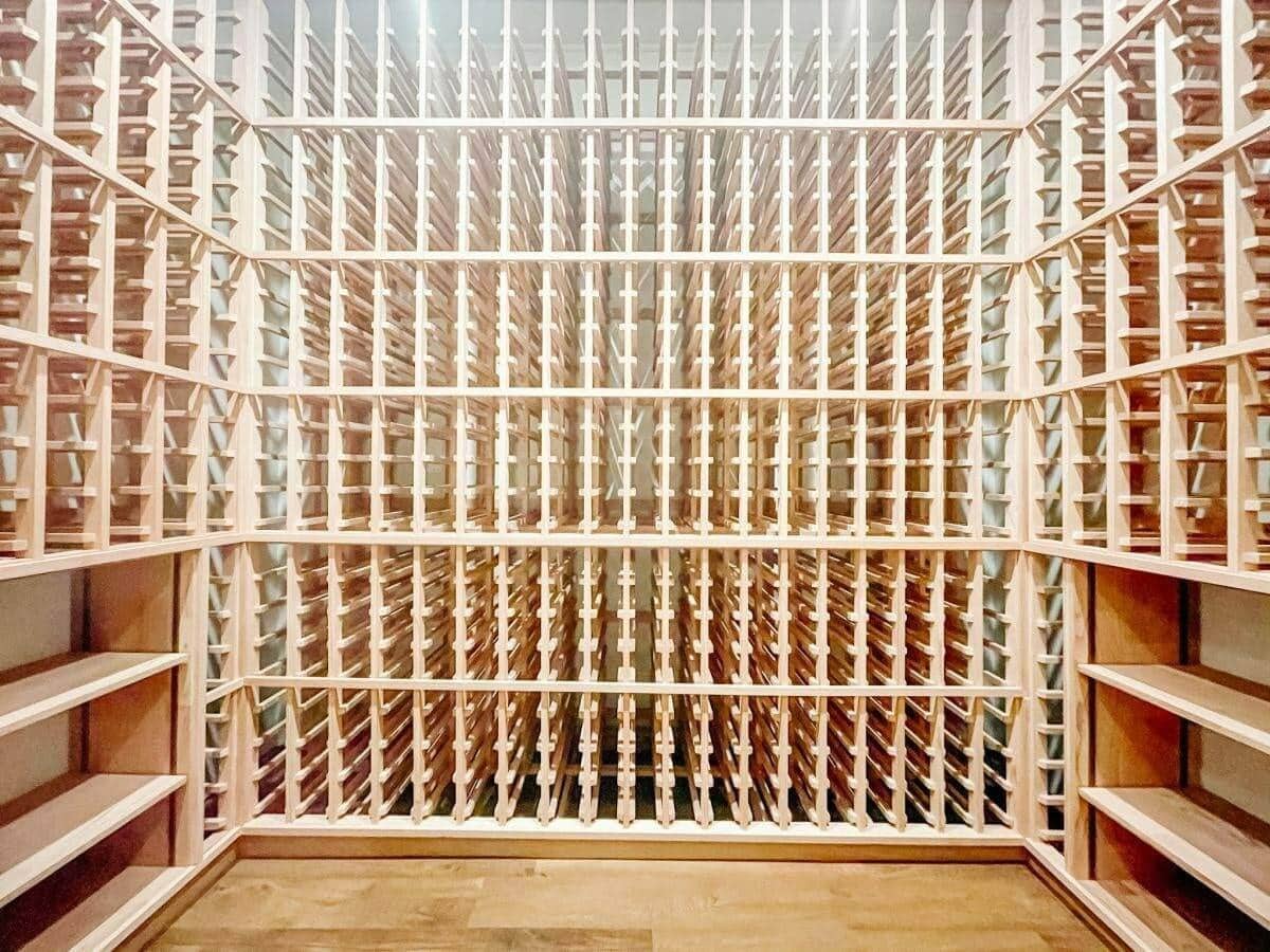 Empty wooden wine racks wrap around three walls above a wood floor.
