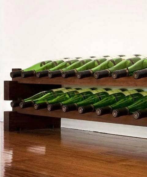 Wooden wine rack kit holding green bottles on a plain background
