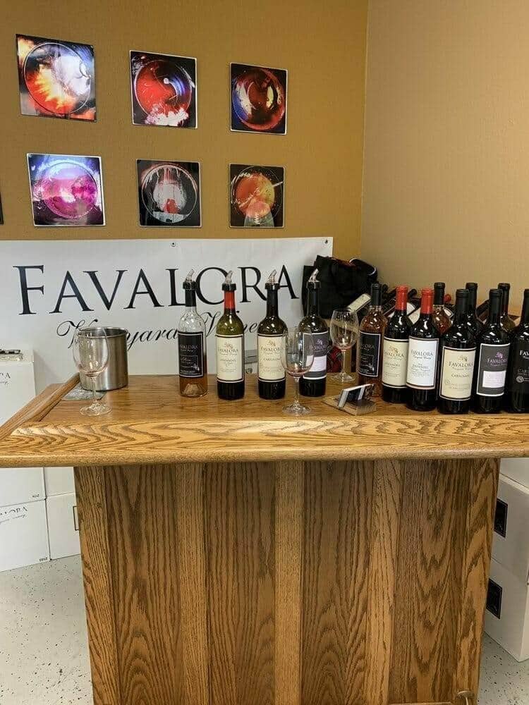 Favalora Vineyards tasting room bar with wine bottles and framed art