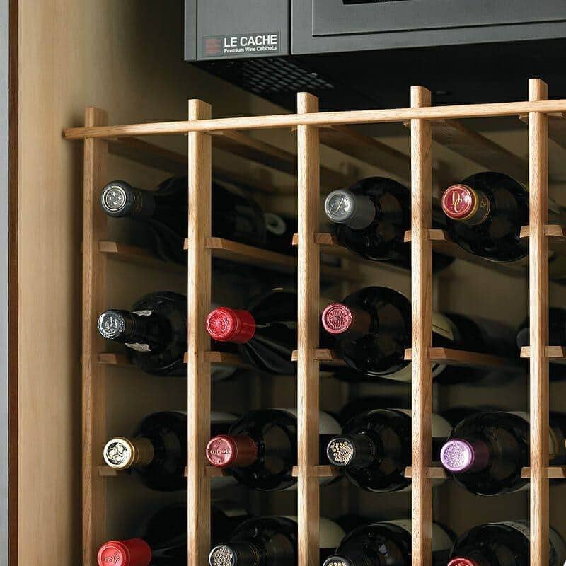 Close-up of wine bottles in Le Cache cabinet wood racking under cooling unit