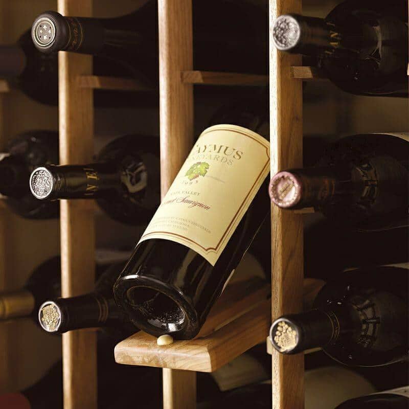 Close-up of a labeled wine bottle resting in wood cellar racking