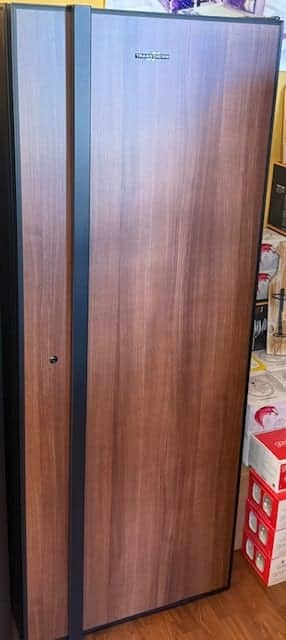 Transtherm Utility wine cabinet in tobacco wood finish standing beside stacked moving boxes