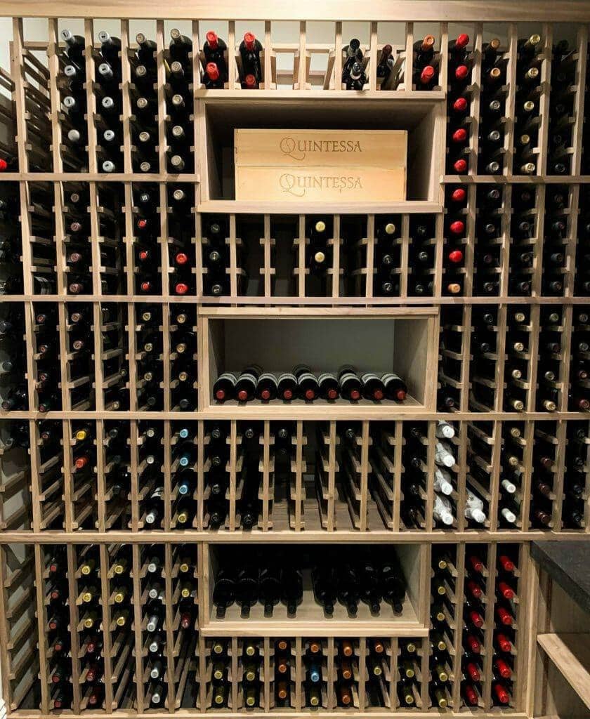 Wooden bottle slots surround open cubbies holding wine cases.