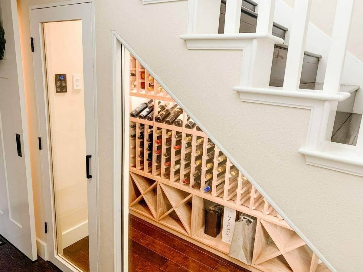 Wooden bottle slots and diamond bins follow the angle of a staircase behind glass.