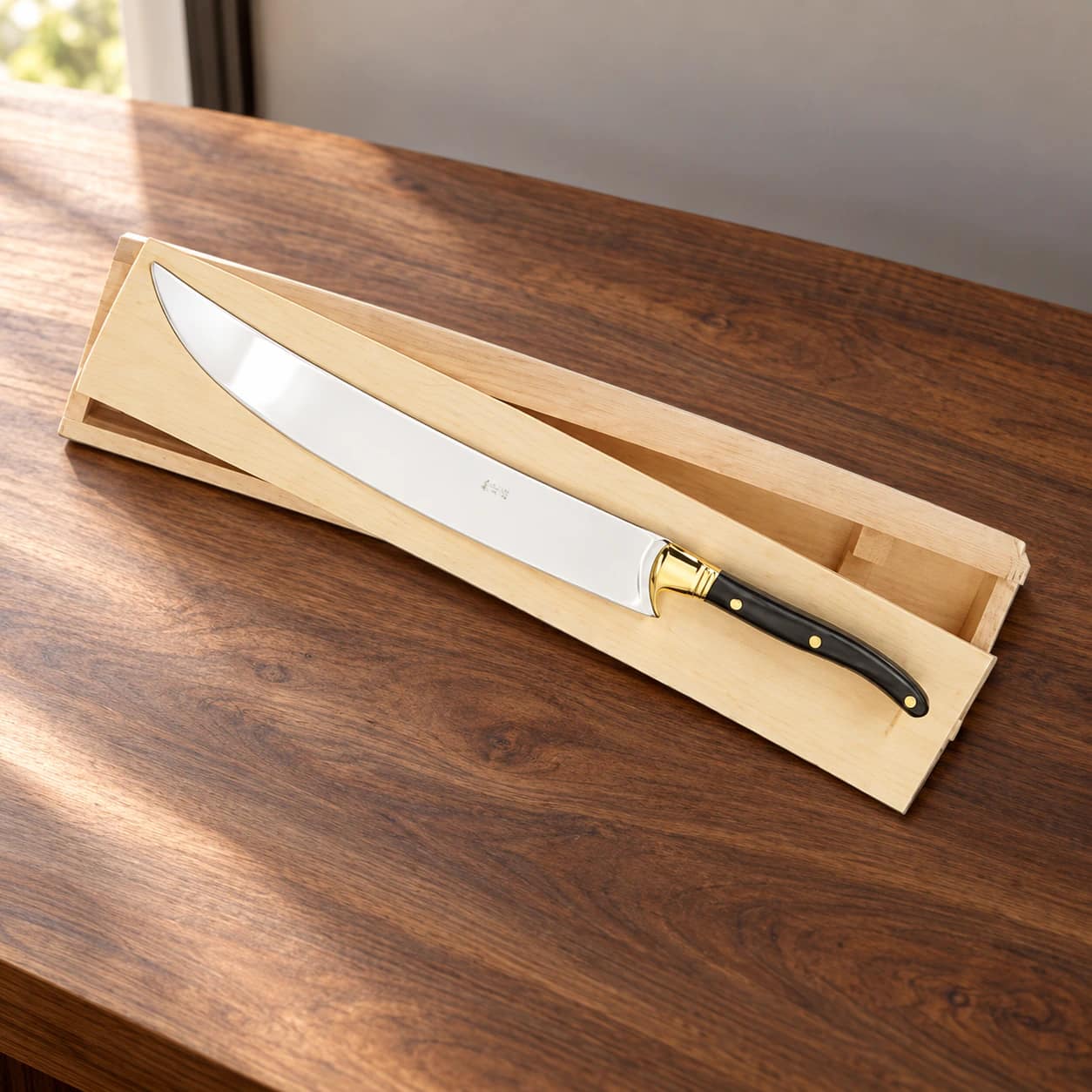 Champagne saber with black handle and wooden presentation box on a walnut counter