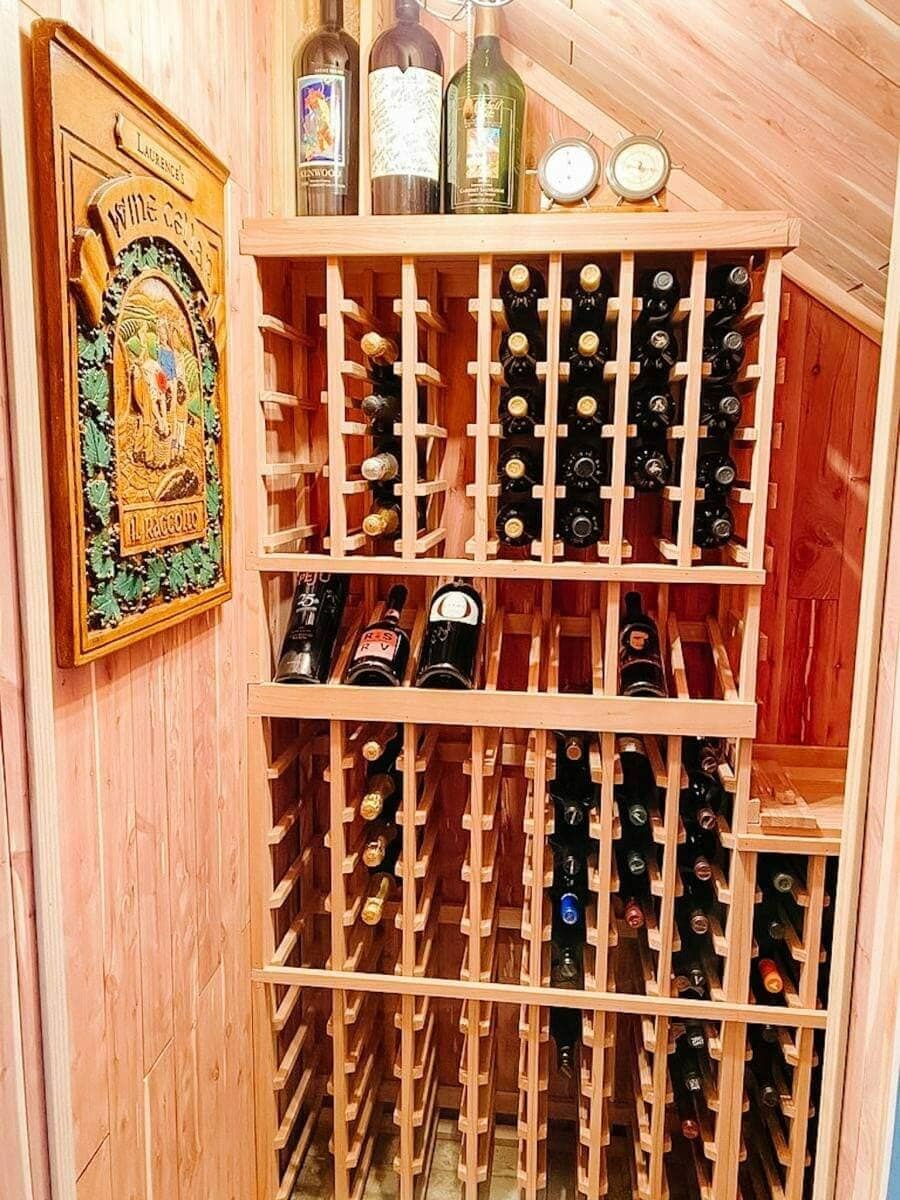 Wooden bottle racks follow a sloped ceiling beside a framed wine poster.