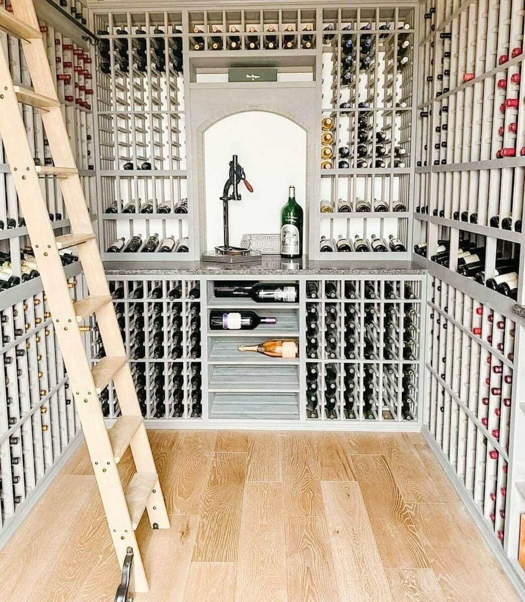 A wooden ladder stands beside gray bottle racks and an illuminated central display alcove.