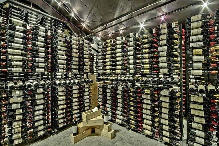 Floor-to-ceiling wine cellar with wood-and-metal racks holding hundreds of bottles