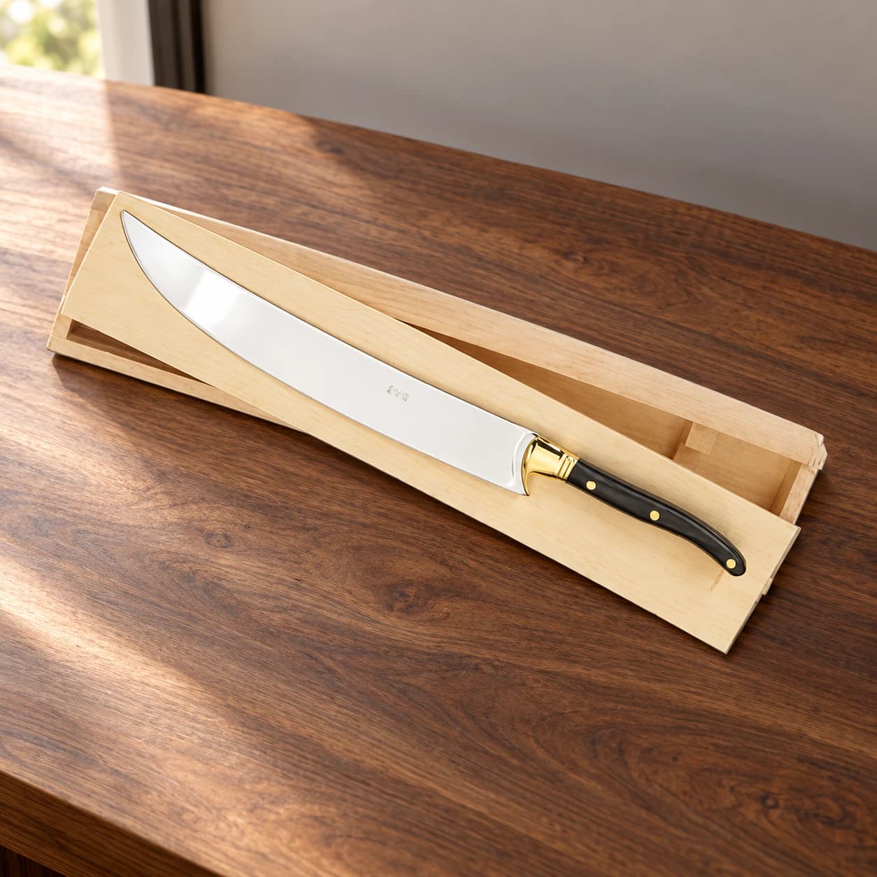 Champagne saber with black handle and wooden presentation box on a walnut counter