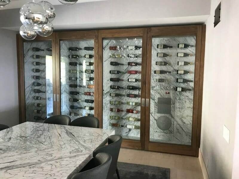 Wood-framed glass doors enclose a bottle display beside a stone-patterned dining table.