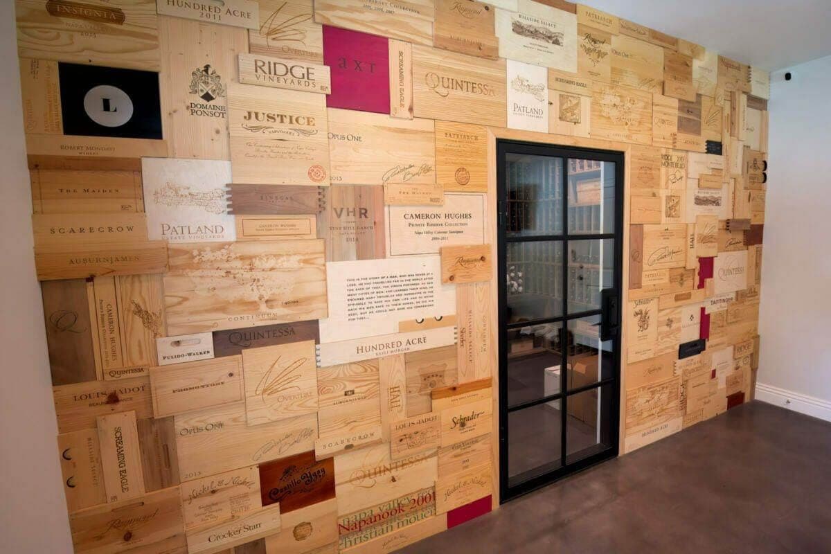 Wooden wine-crate panels surround a black-framed glass cellar door.