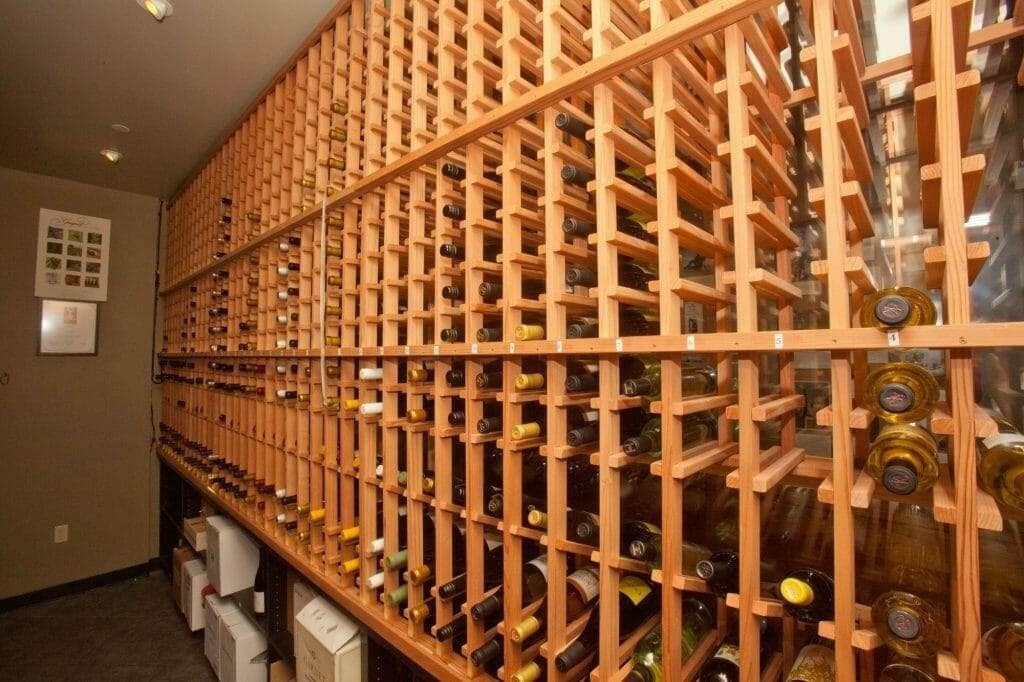 Rows of wooden bottle slots line a long storage wall above stacked wine cases.