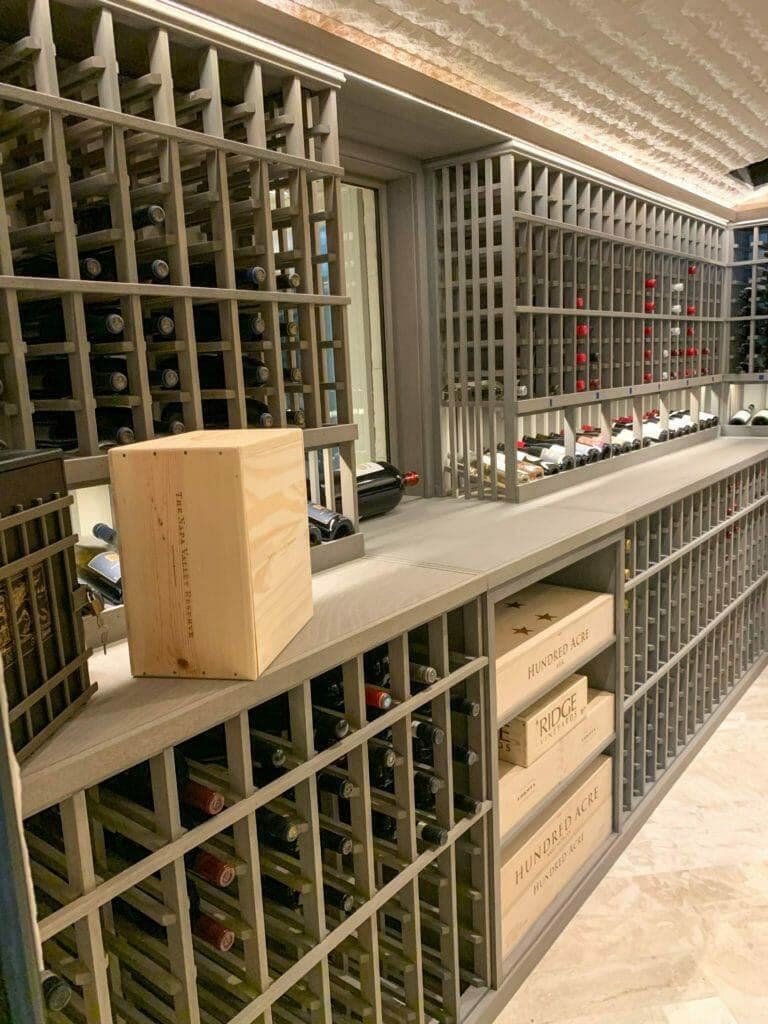Gray wooden racks combine bottle slots, a lit display row and lower case cubbies.