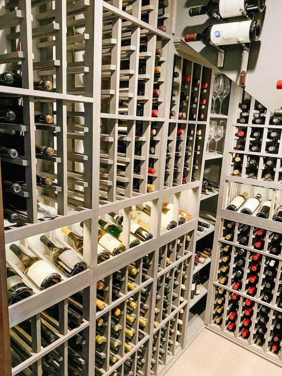 Gray racks combine individual bottle slots, a lit display row and shelves for stemware.
