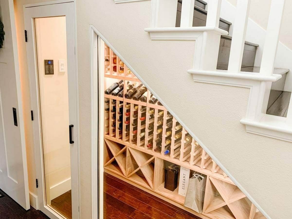 Wooden bottle slots and diamond bins follow the angle of a staircase behind glass.