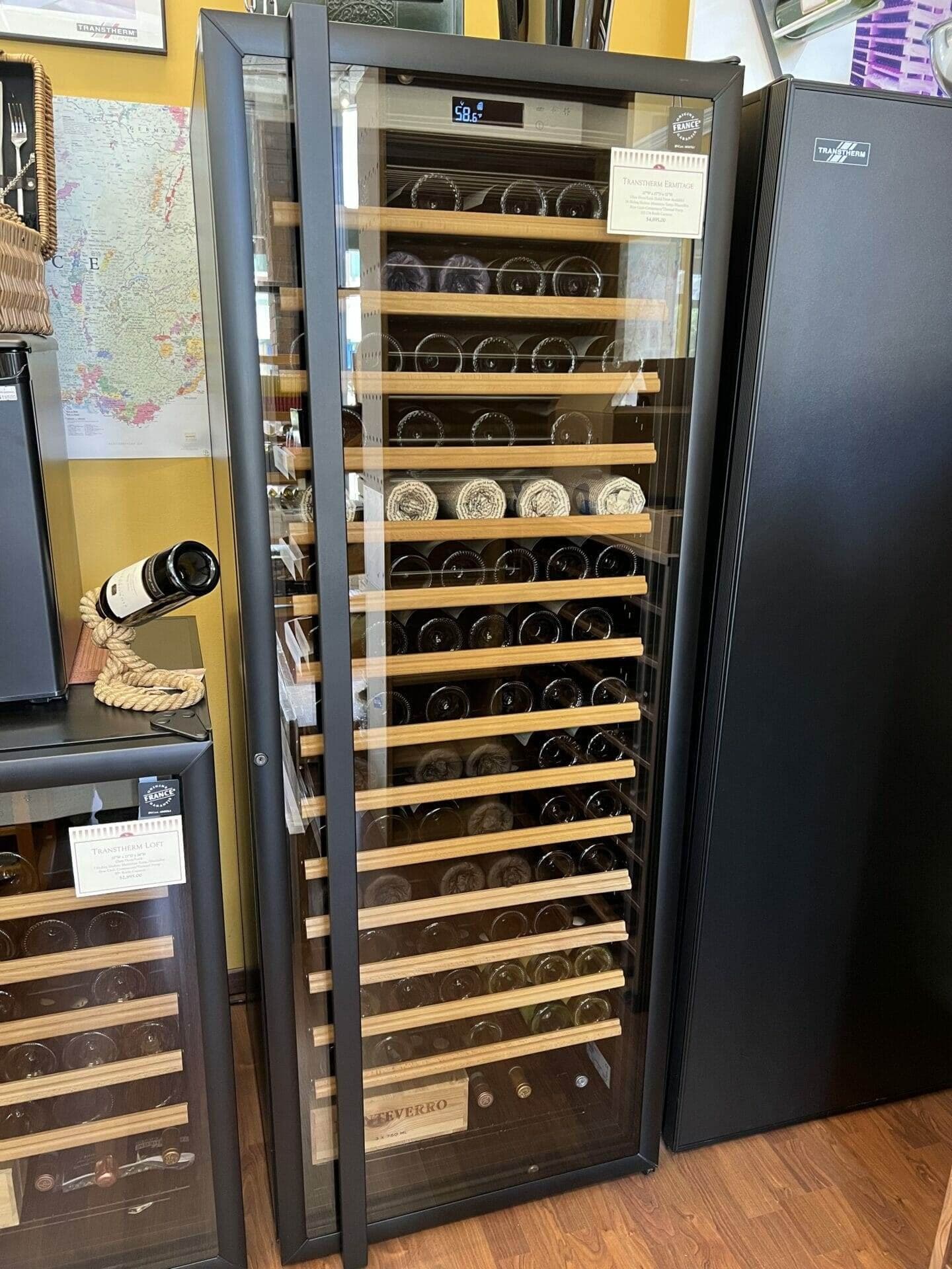 A glass-door wine cabinet displays bottles on wooden shelves beside a solid-door cabinet.