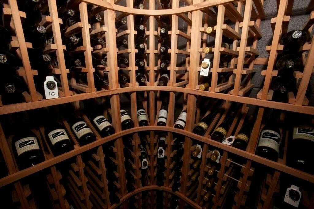 Arched wood wine rack storage room with bottles on both walls