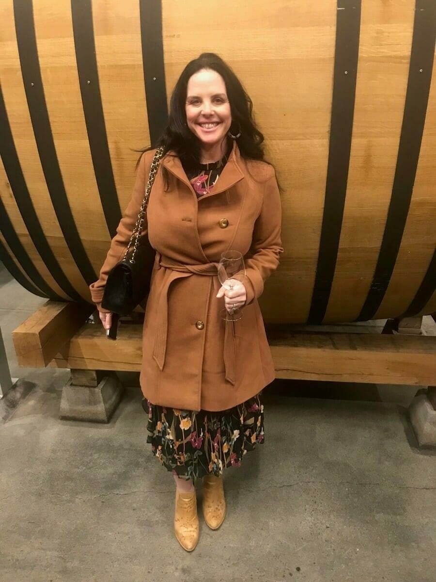 Woman posing with a wine glass beside a large wood barrel