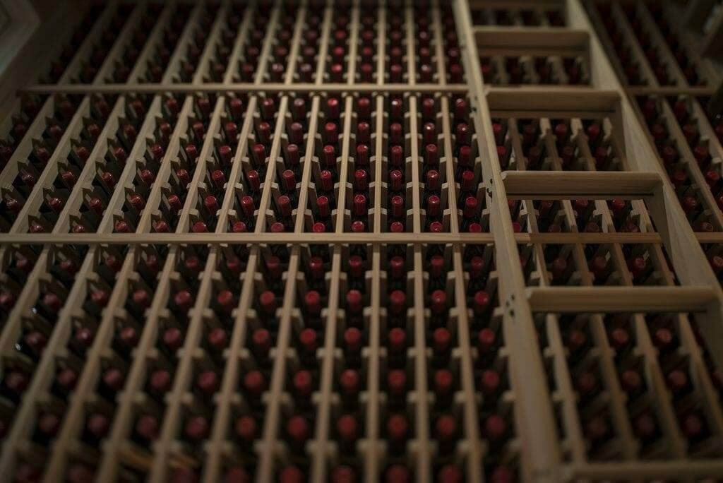 Close angled view of a wood wine rack packed with labeled bottles