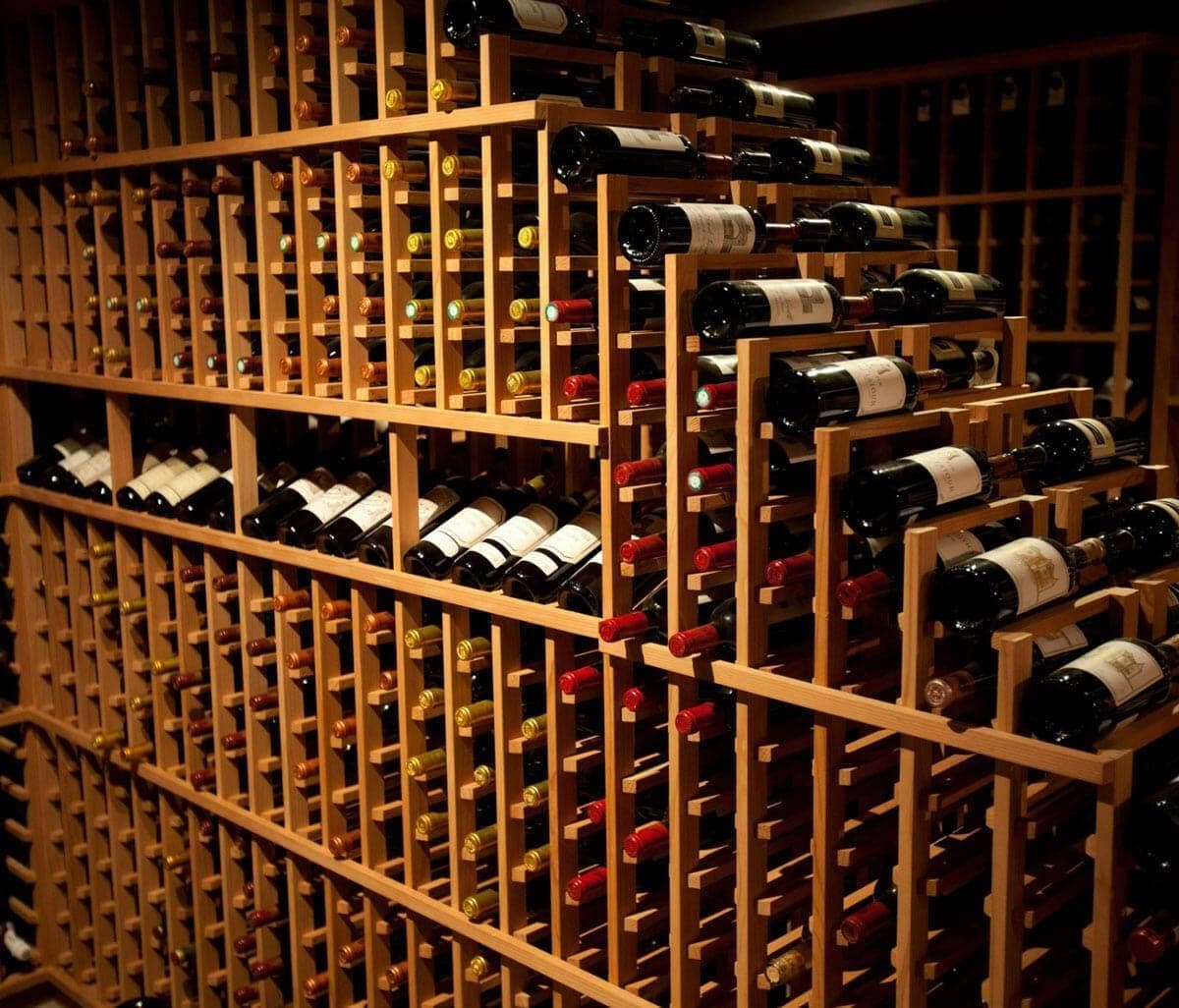 Close-up of a wood wine rack filled with labeled red wine bottles