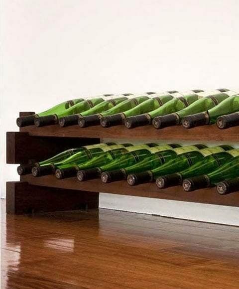 Wooden wine rack kit holding green bottles on a plain background