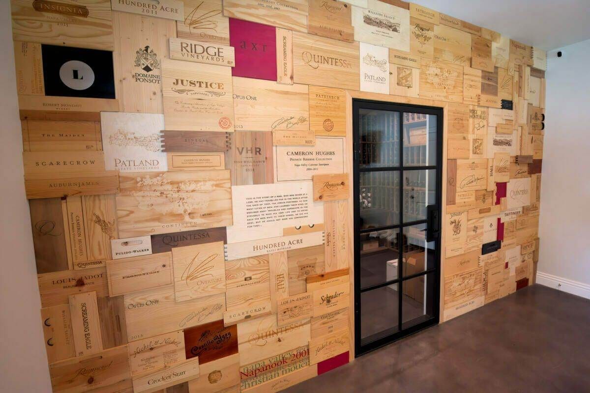 Wooden wine-crate panels surround a black-framed glass cellar door.