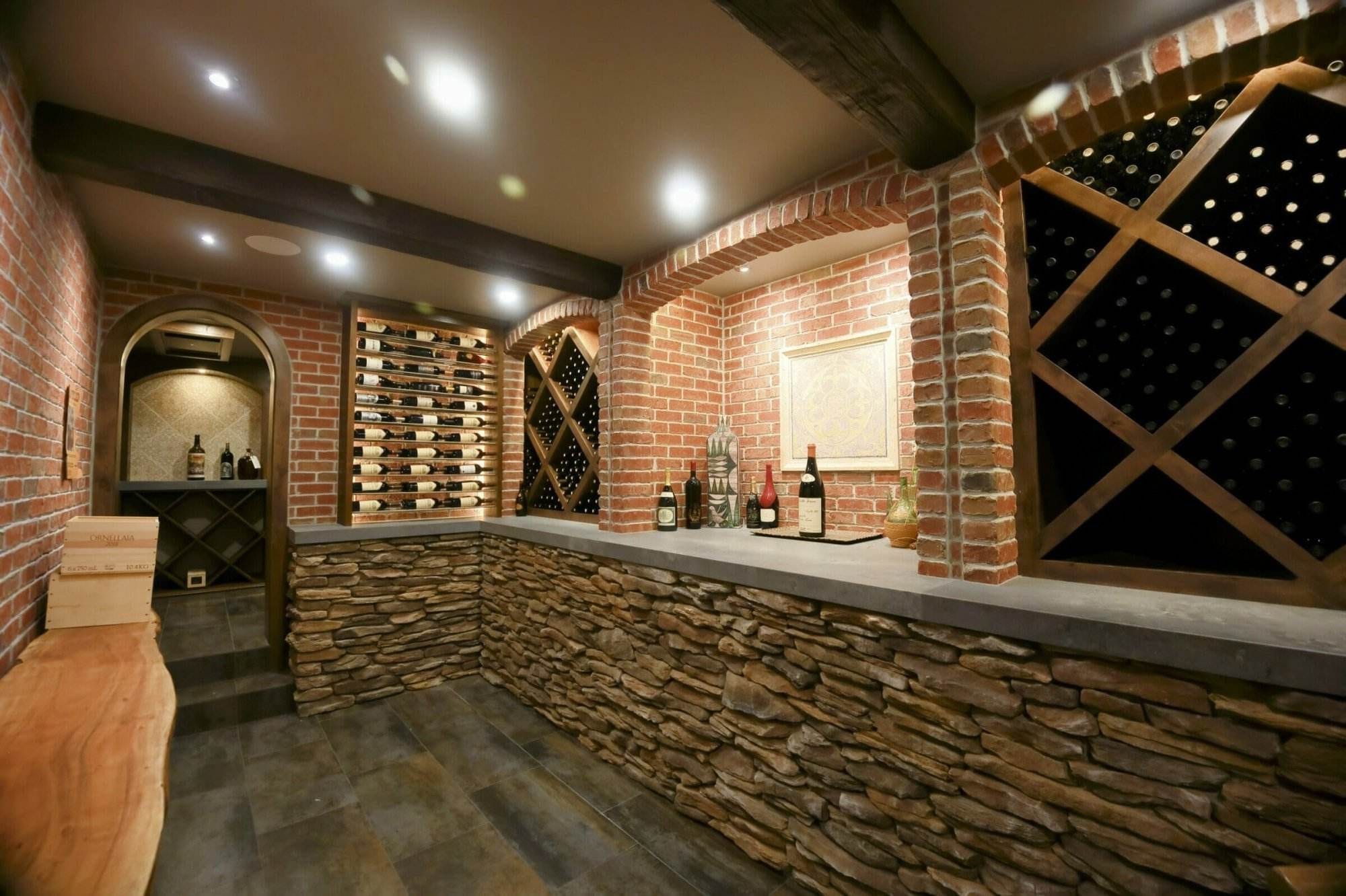 A brick arch frames a cellar bar between label-forward racks and wooden diamond bins.