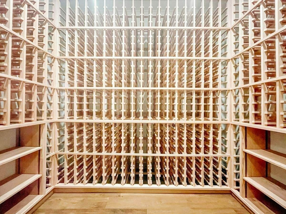 Empty wooden wine racks wrap around three walls above a wood floor.
