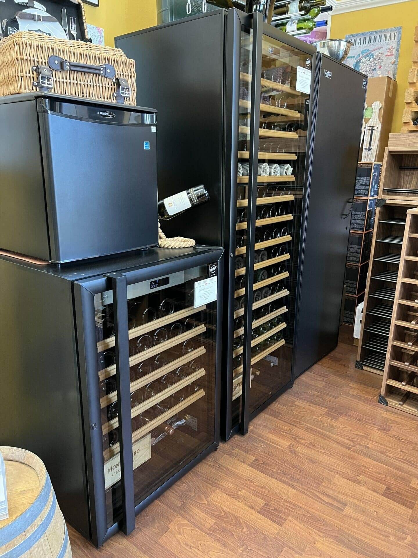 Wine cabinets and a compact refrigerator stand beside wooden racks in the showroom.