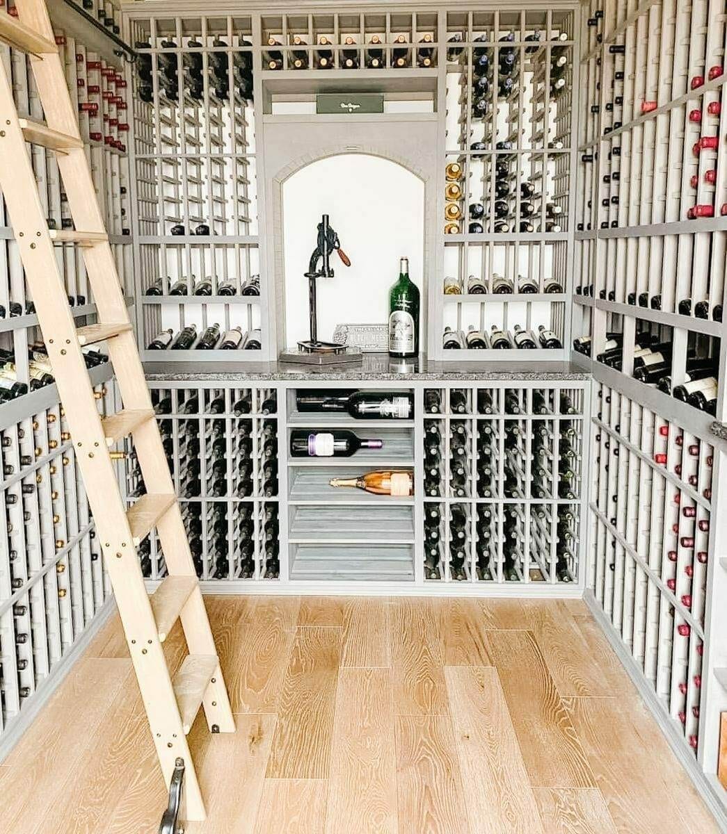 A wooden ladder stands beside gray bottle racks and an illuminated central display alcove.