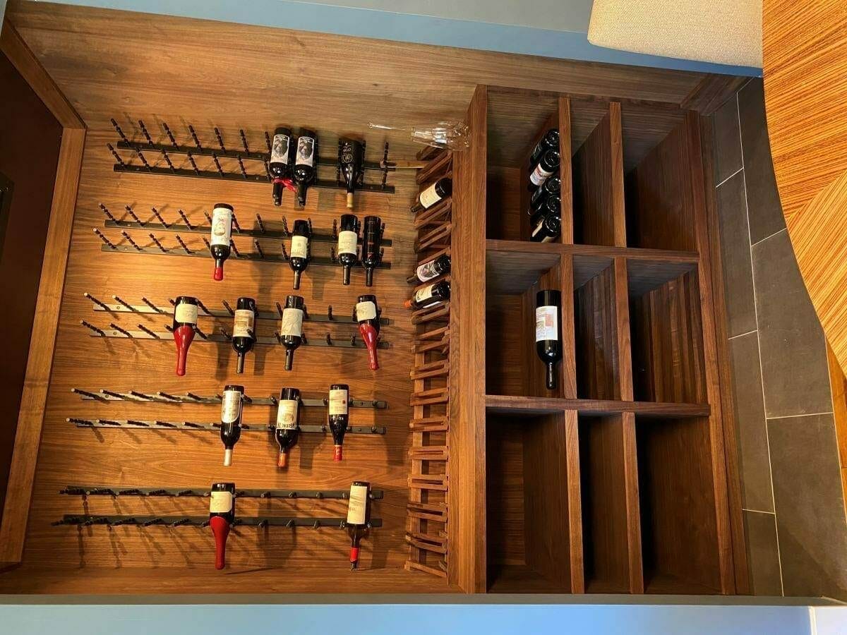 Walnut wine racking with clear stain and black metal pegs holding bottles