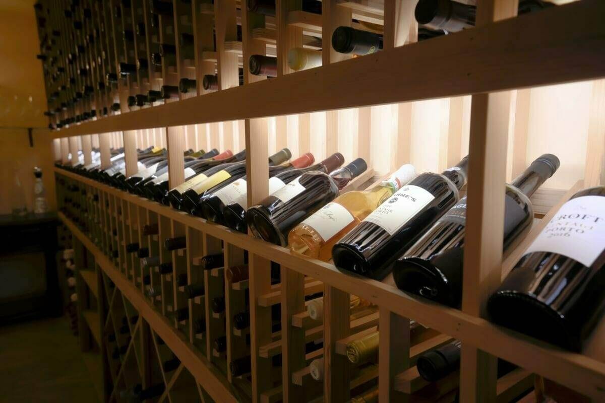 Close-up of a wooden wine rack filled with labeled bottles in a cellar.