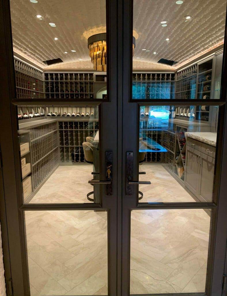 Wine cellar viewed through glass doors with a lit chandelier inside