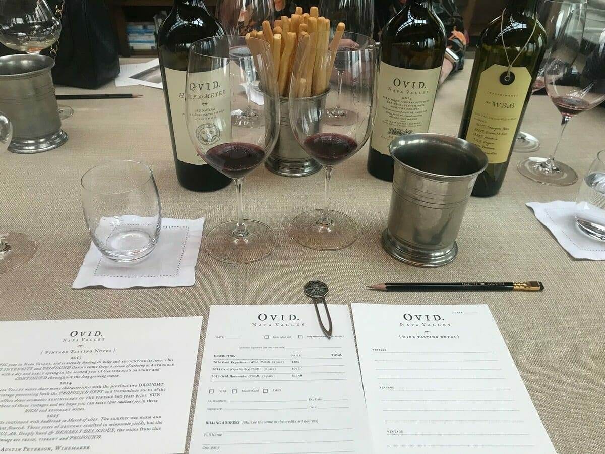 OVID wine tasting table set with glasses, bottles, and tasting notes
