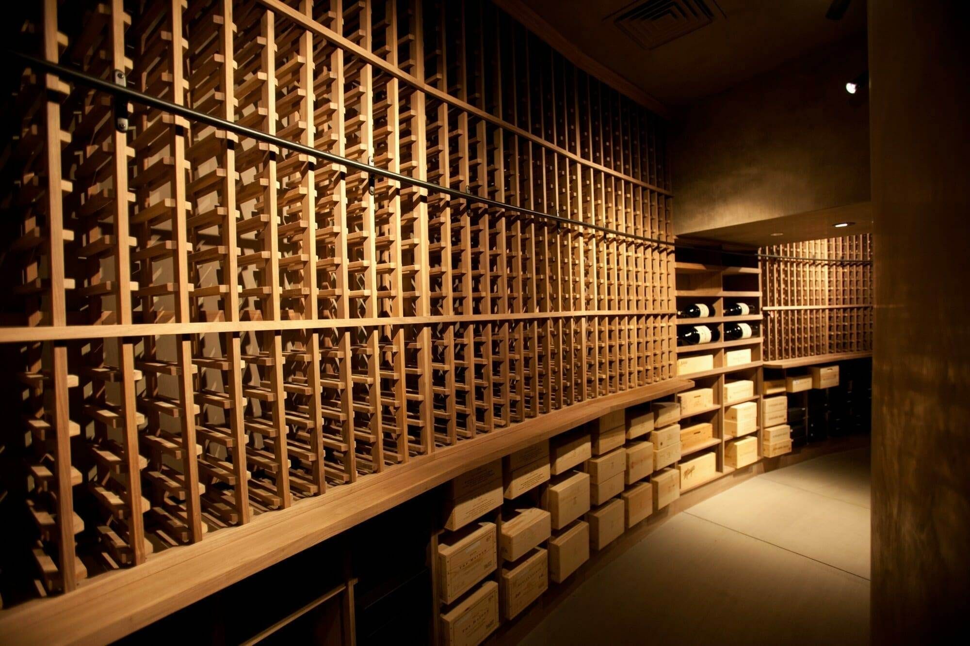 Angled view down a wine cellar row of wooden bins and storage boxes