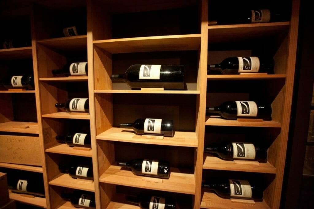 Wood wine cubby shelves displaying labeled bottles at an angle