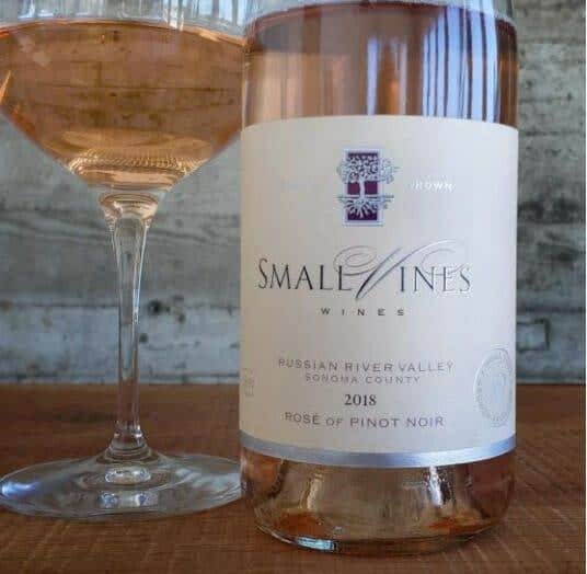 Small Vines Rose of Pinot Noir bottle and glass on wood table