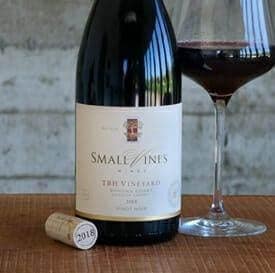 Small Vines TBH Vineyard Pinot Noir bottle with poured glass on wood table