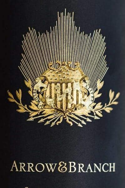 Arrow and Branch wines gold crest logo embossed on dark bottle
