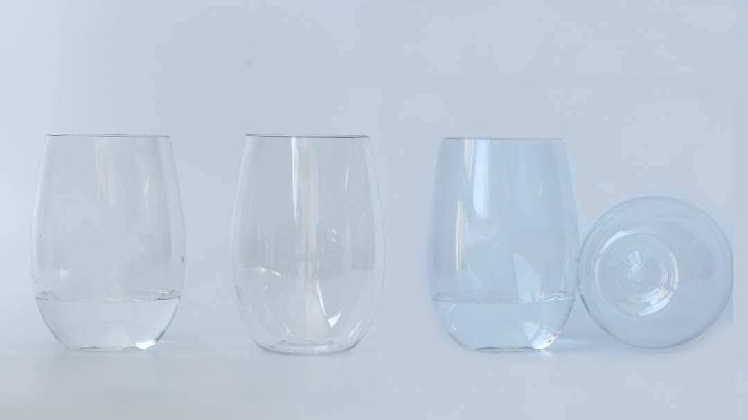 Four stemless Tritan wine glasses arranged on white background