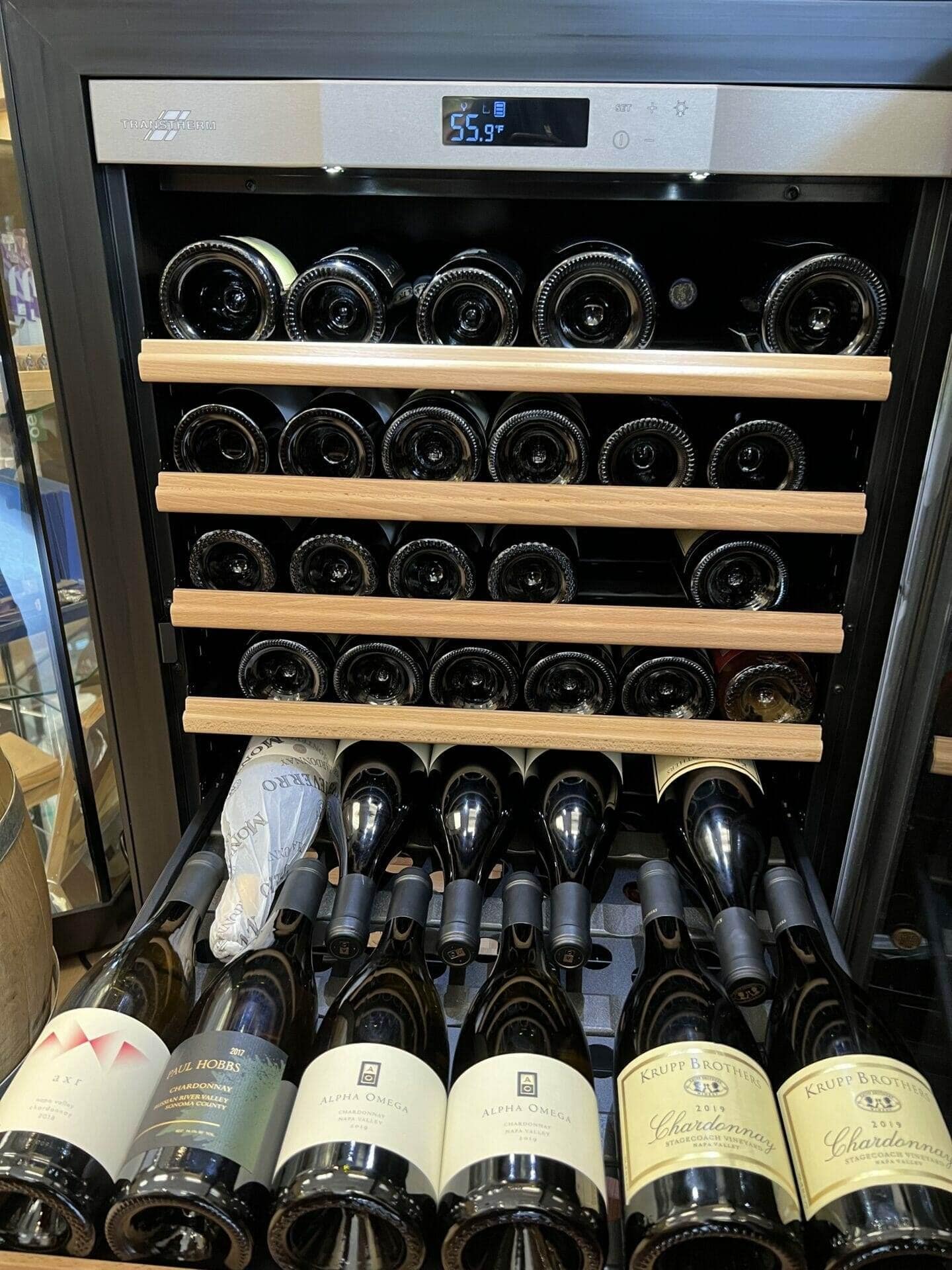 Transtherm wine cabinet with wood-slat shelves, bottles above a drawer of Chardonnay