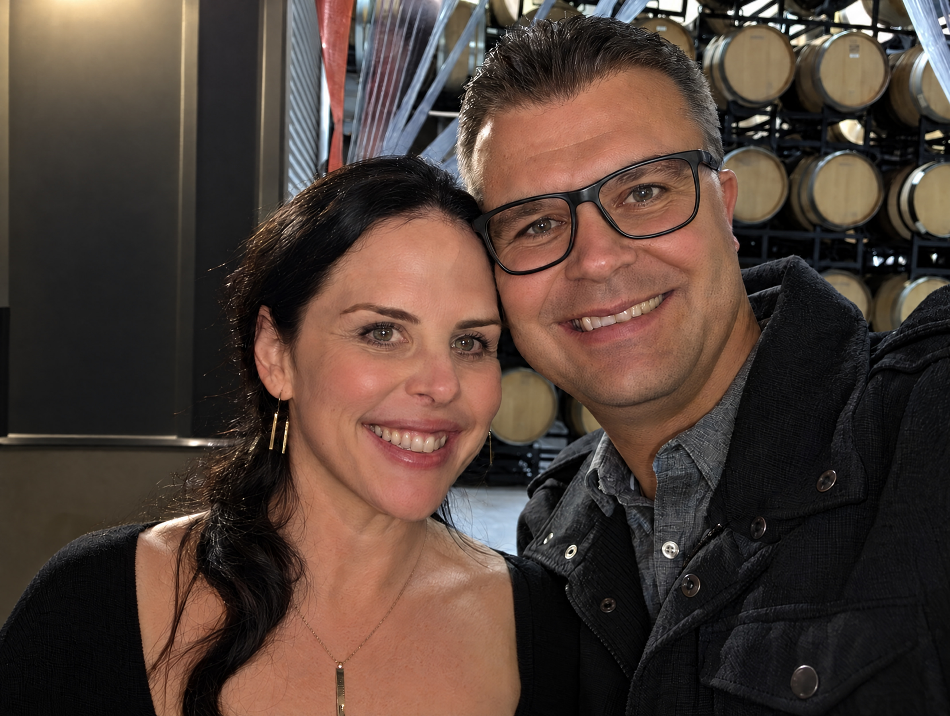 Cari and Mike Vecchia smiling in a wine cellar, with Cari on the left and Mike wearing glasses on the right