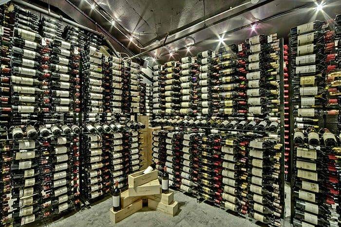 Floor-to-ceiling wine cellar with wood-and-metal racks holding hundreds of bottles