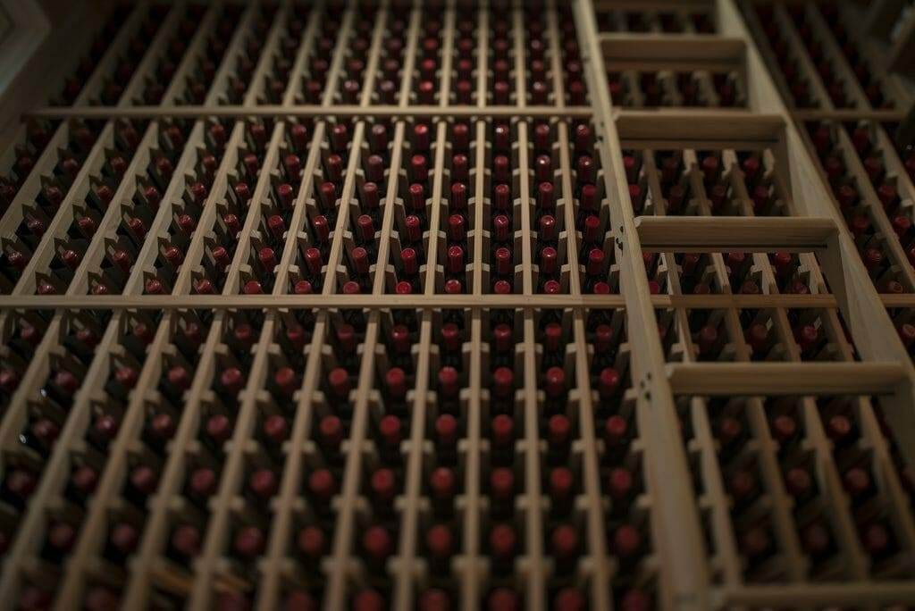 Close angled view of a wood wine rack packed with labeled bottles