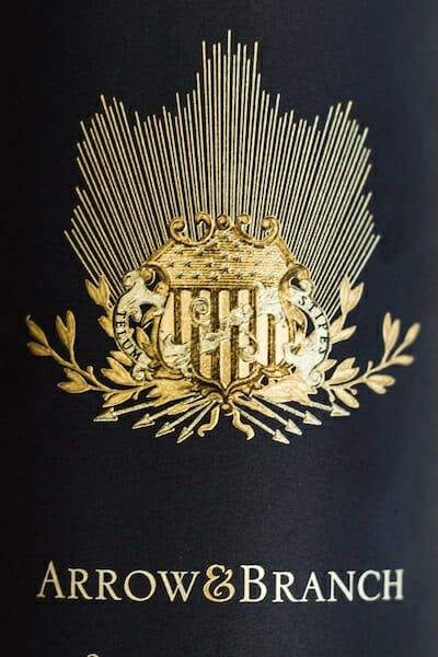 Arrow and Branch wines gold crest logo embossed on dark bottle